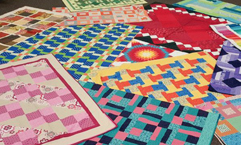 Overlapping quilted blankets laid out on a floor