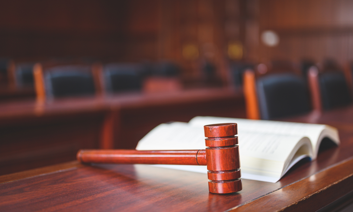 an open book and a gavel lying on a table at the front of a courtroom.